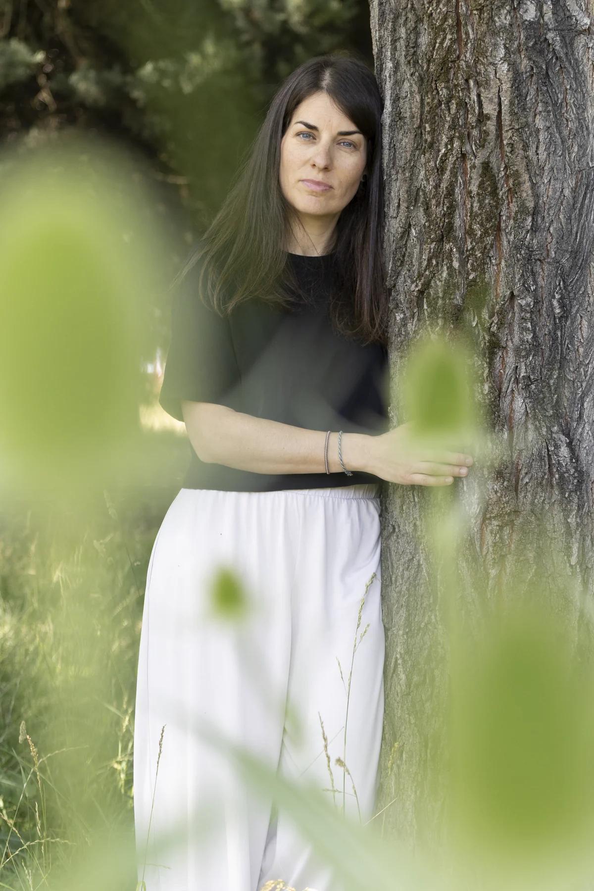 Esther Mambrilla apoyada en un árbol en un entorno natural