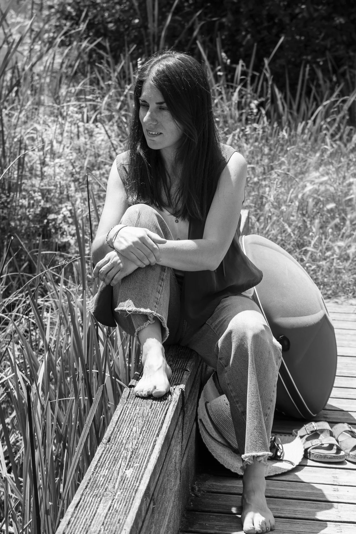 Esther Mambrilla sentada en una pasarela de madera con la funda de su handpan