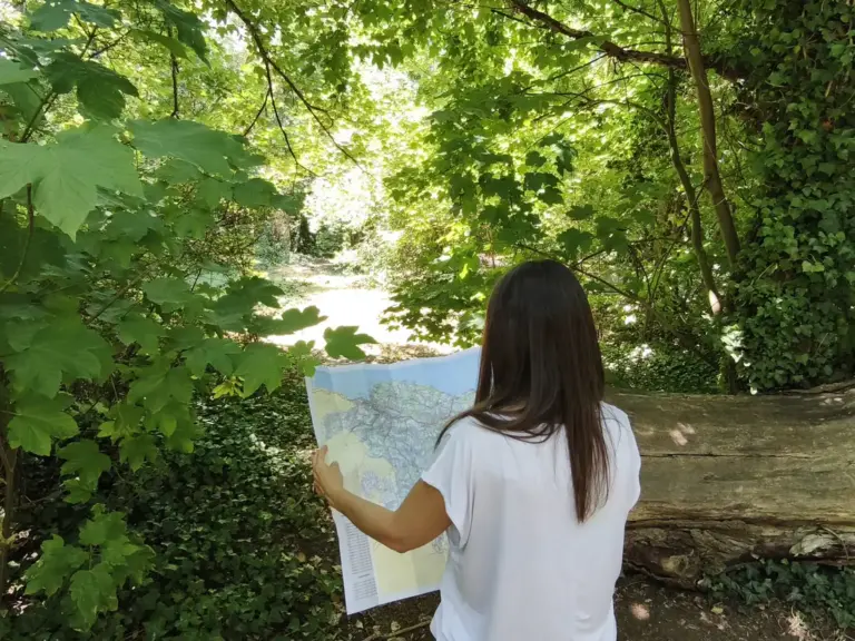 Esther Mambrilla consulta un mapa desplegado en un sendero entre árboles