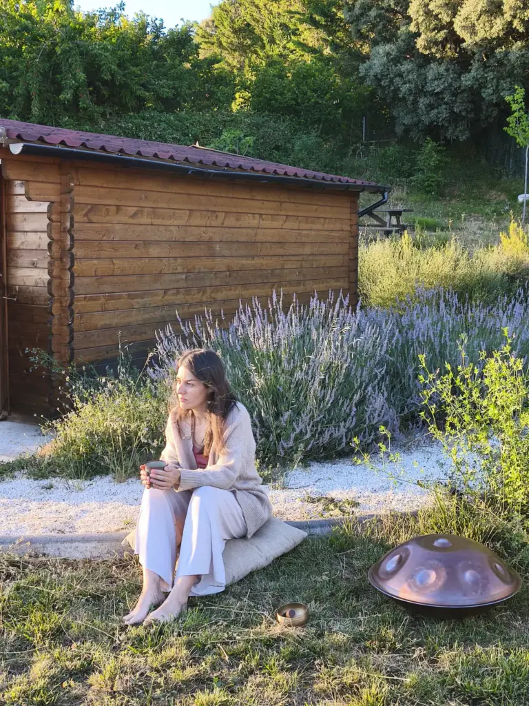 Esther Mambrilla sentada junto a una cabaña de madera con su handpan